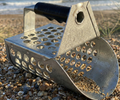 Heavy duty metal sand scoop with hexagonal sifting holes and black rubber grip, designed for metal detecting on shingle beaches